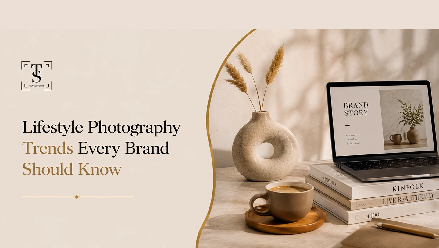 Modern workspace with lifestyle photography setup, featuring a laptop, stacked books, a ceramic vase with pampas grass, and a coffee cup.